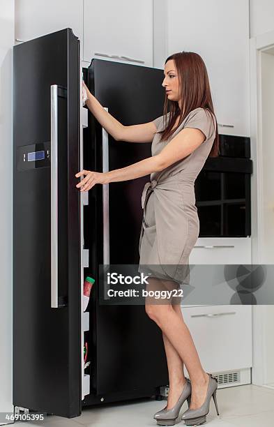 Young Woman In The Kitchen Stock Photo - Download Image Now - Reaching, Freezer, One Woman Only