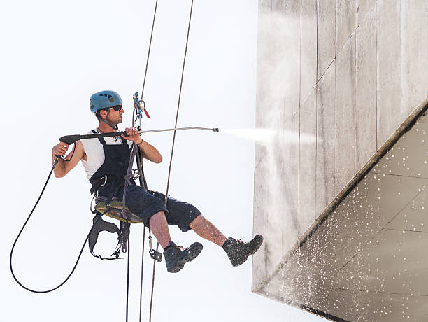Man hanging high up and washing a building.