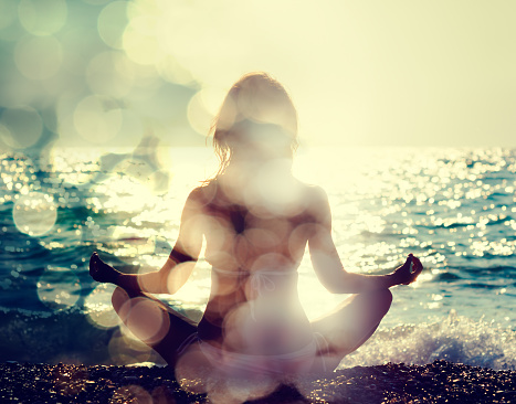 Woman Practicing Yoga by the Sea. Rear View. Double Exposure Filtered Photo with Bokeh. Soul Concept.
