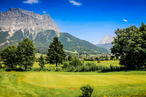 Garmisch area, Germany - June 30, 2012:  Germany's highest mountain, the Zugspitze looming over the green fields below on a summer's day in the Oberbayern region of Bavaria.