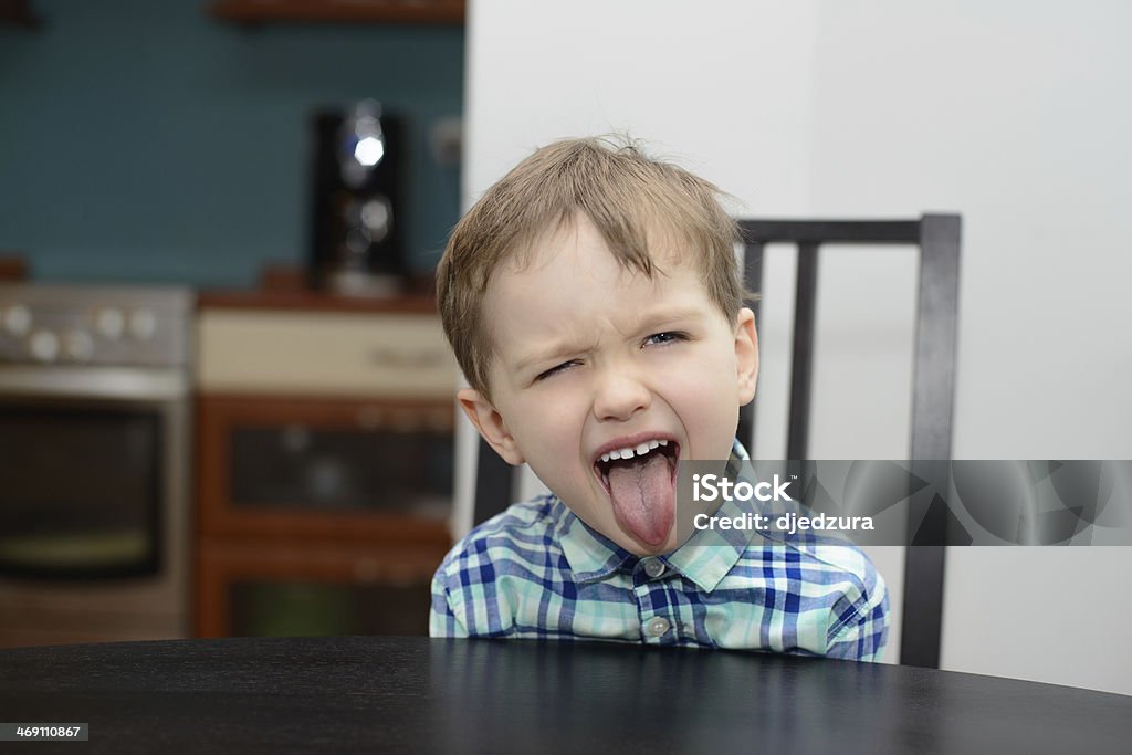 4 year old boy shows his tongue 4 year old boy shows his tongue while sitting at the table Disgust Stock Photo