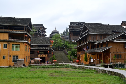Chengyang, China - April 21, 2014: tourists in the background sightseeing Dong village with the old Drum Tower in the background. It is one of the eight Dong ethnic minority villages nearby the Chengyang Wind and Rain Bridge in Sanjiang County, a popular tourist attraction in North Guangxi