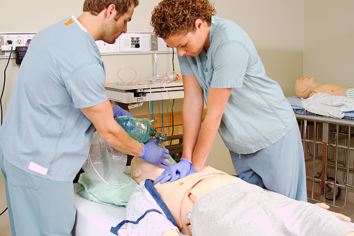Two medical staff practicing CPR on mannequin