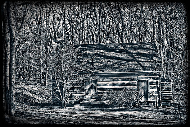 A black and white photo of an old creepy cabin in the woods.
