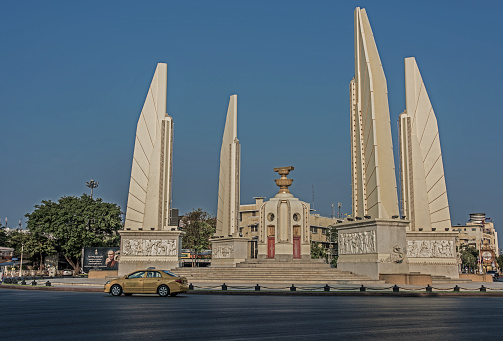 Democracy Monument Bangkok with yellow taxi