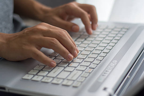 istock Delicate hands typing away on a white keyboard 469122398