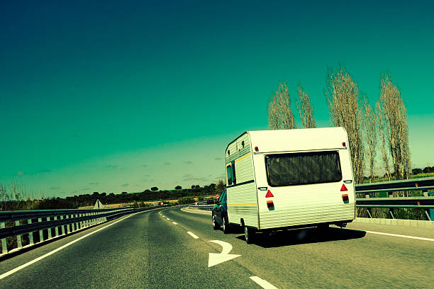 Back view of a passenger car pulling a caravan on the road.