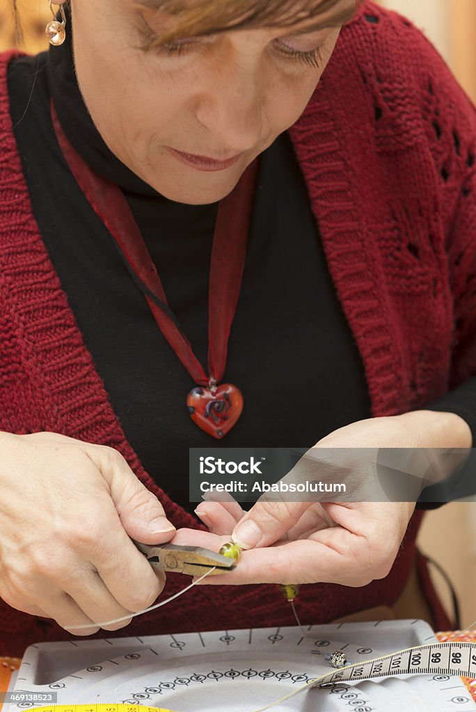 Woman Making Necklace at Home, Slovenia Woman making necklaces at home, Slovenia. Adult Stock Photo