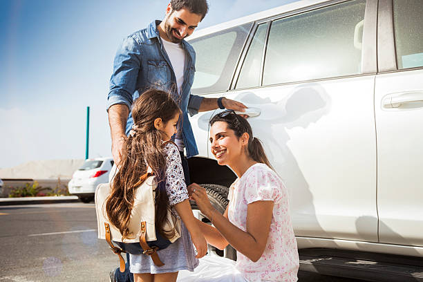 Young family taking daughter to school by car Young family in Dubai - UAE, taking their little girl to school by car in the morning in Jumeirah district. They are happy in a sunny day. leaving a tip stock pictures, royalty-free photos & images