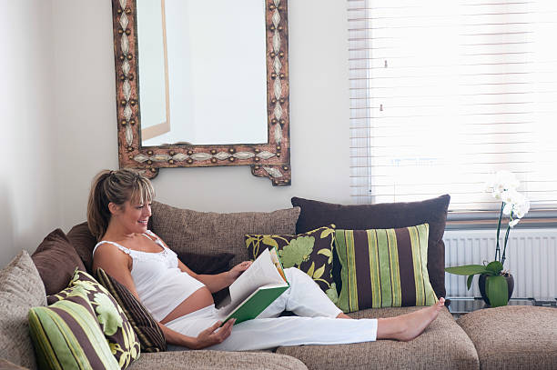 istock Pregnant Woman Reading Book On Sofa 469140309