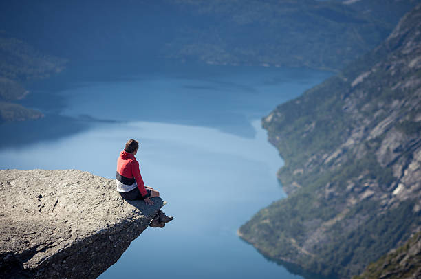 mann sitzt auf trolltunga rock in norwegen - tongue mountain stock-fotos und bilder
