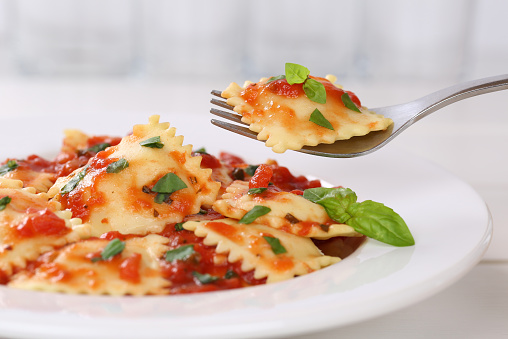 Eating Ravioli with tomato sauce meal with basil on a plate