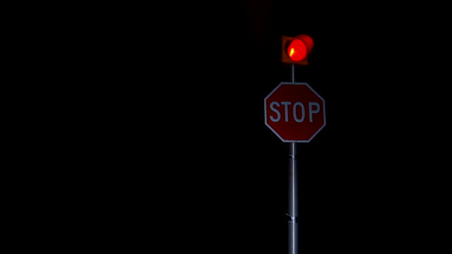 Stop sign red light flashing on dark rural countryside intersection