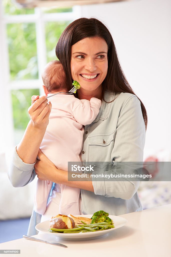 Mother With Baby Eating Healthy Meal In Kitchen 2015 Stock Photo