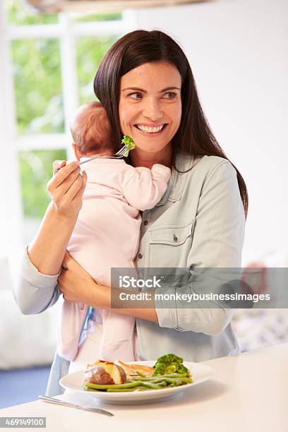 Mother With Baby Eating Healthy Meal In Kitchen Stock Photo - Download Image Now - 2015, 30-39 Years, Adult