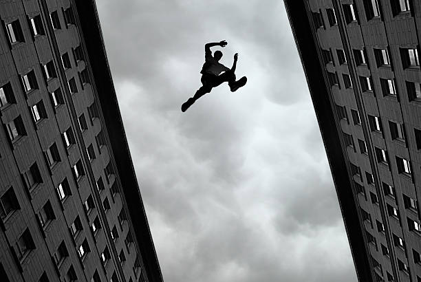 mann, springen über gebäude - le parkour stock-fotos und bilder