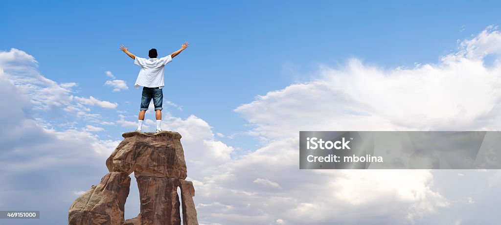 Winner man standing on the top of mountain Man with arms raised in the sky, winner success concept High Up Stock Photo