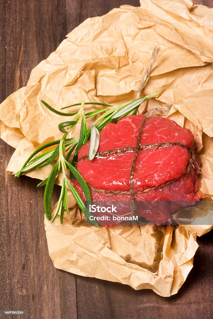 Fresh raw steak with peppers, rosemary, salt on wooden background Fresh raw steak with peppers, rosemary, salt on wooden background with craft paper decoration 2015 Stock Photo