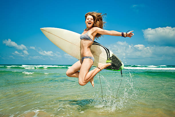 Surfer girl in bikini on surfboard on the beach at sunset.active sport lifestyle and summer vacation,relax concept.
