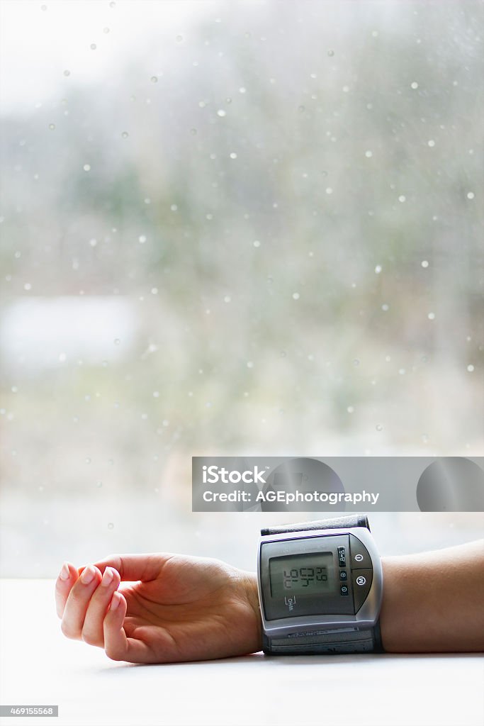Woman's hand with blood pressure measuring device Woman's hand with blood pressure measuring device showing low blood pressure near a window in winter 2015 Stock Photo