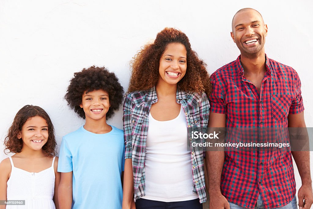 Family Standing Outdoors Against White Wall Family Standing Outdoors Against White Wall,  Smiling To Camera 20-29 Years Stock Photo