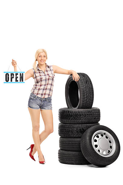 istock Woman holding an open sign by a stack of tires 469159108