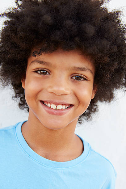 istock Smiling Young Boy Standing Outdoors Against White Wall 469159244