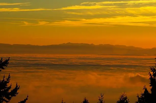 Photo of sea and mountains with thick fog at sunset