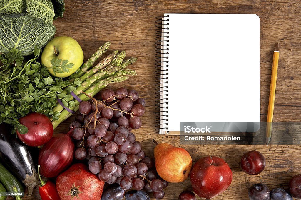 Cookbook. Copy space studio photography of open blank ring bound notebook surrounded by a fresh vegetables and pencil on old wooden table Dieting Stock Photo