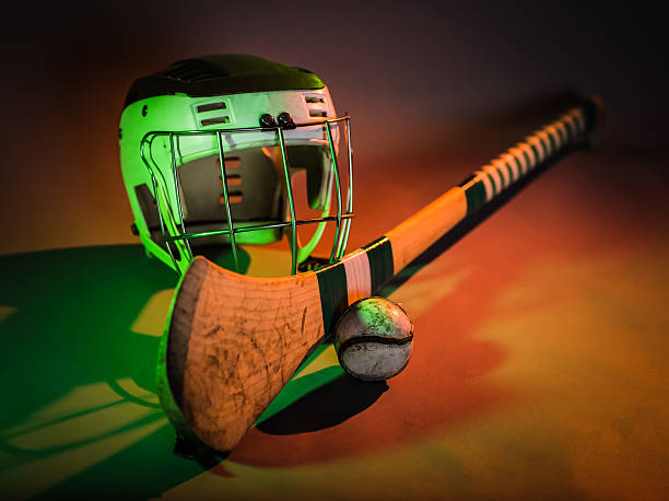 a studio shot of a hurling stick, ball, and helmet in colorful green and orange light. irish