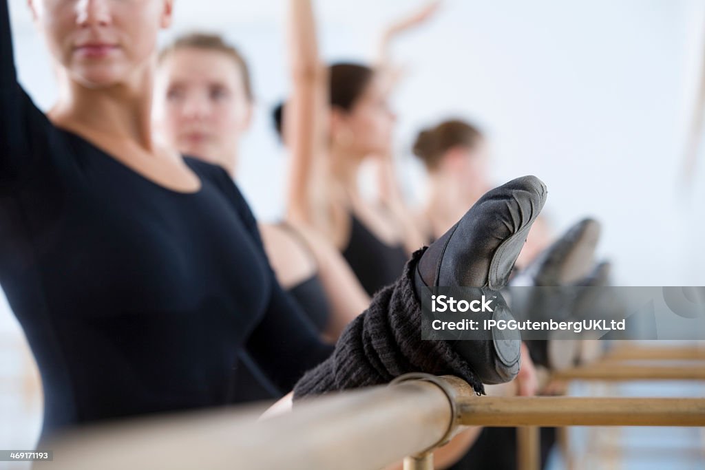 Ballet dancers stretching their legs and practicing Row of ballet dancers practicing at the barre in rehearsal room Activity Stock Photo
