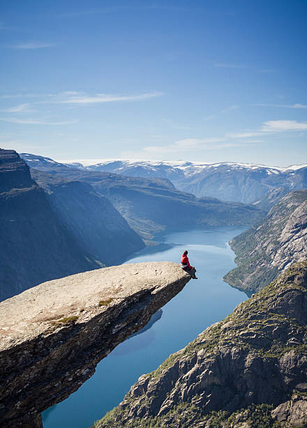 mann sitzt auf trolltunga rock in norwegen - tongue mountain stock-fotos und bilder