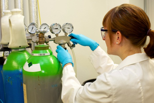 Female lab technician operating the valves of a gas bottle.