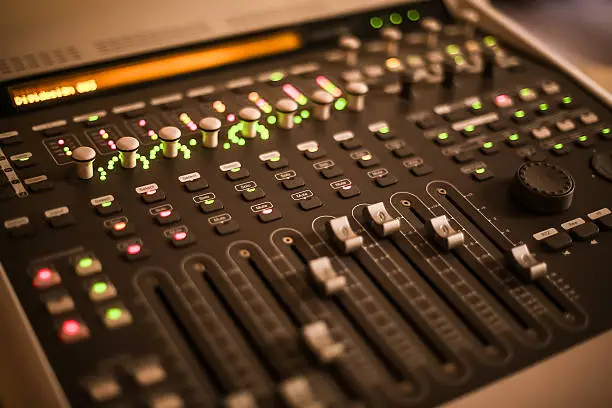 Photo of digital mixing board faders, knobs, buttons and lights