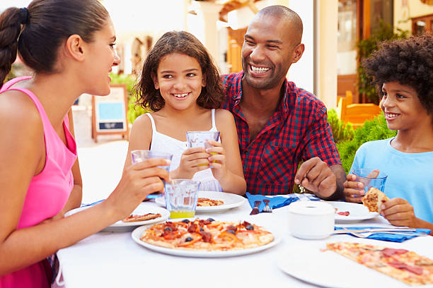 família comer a refeição no restaurante ao ar livre em conjunto - pizza eating african descent lunch imagens e fotografias de stock