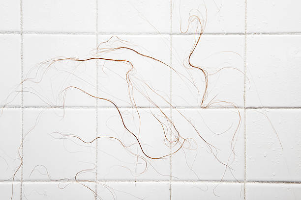 Hair Loss in Shower Close-up of long wet hair strands sticking to shower tiles as a result of chemotherapy. hair strands stock pictures, royalty-free photos & images