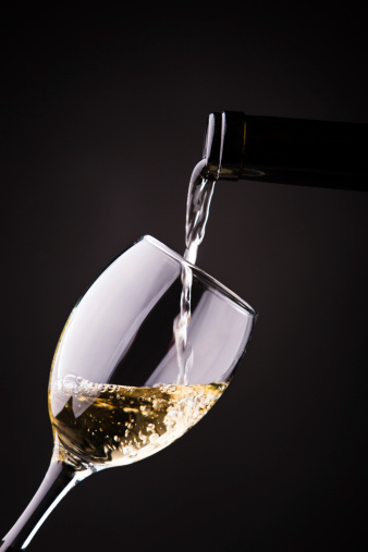 Glass of white wine and a bottle on black background