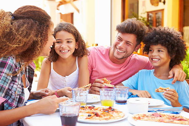 rodzina jedzenie posiłek w restauracji na świeżym powietrzu razem - pizza eating african descent lunch zdjęcia i obrazy z banku zdjęć