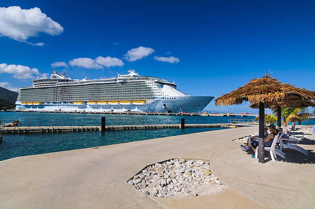 Oasis of the Seas Disembarkation Labadee, Haiti-February 3, 2014:Cruise passengers relax in the shade of palm frond huts as other passengers disembark the Royal Caribbean Cruise ship the Oasis of the Seas for a day of beach activities.  With a passenger capacity of over six thousand, the Oasis of the Seas is the largest cruise ship in the world to date. labadee stock pictures, royalty-free photos & images