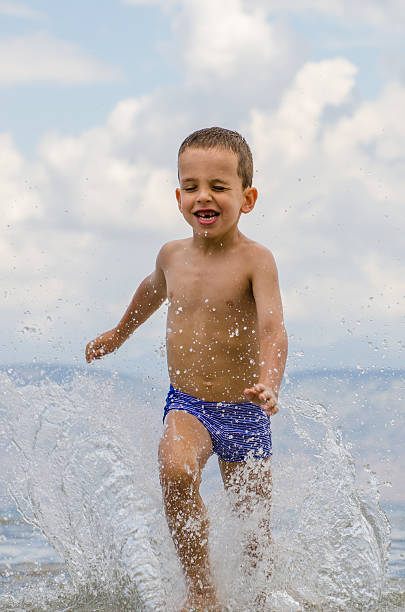 istock Boy running through the water 469195124