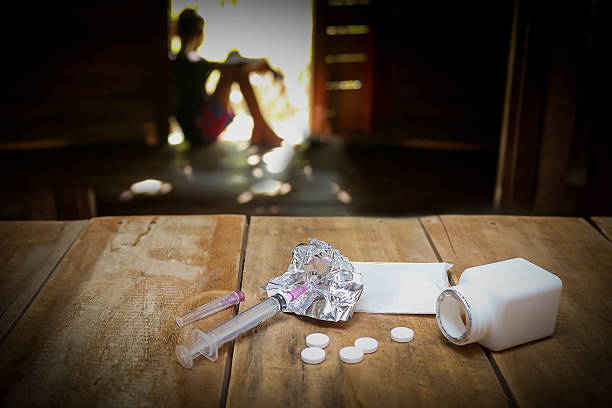 Girl sitting in the background, with drugs on the table stock photo