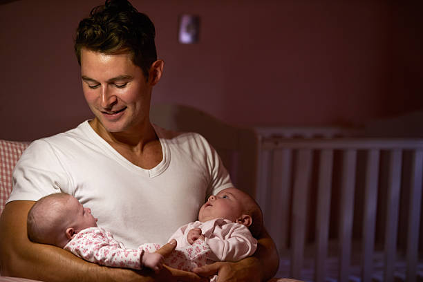 istock A father holding his twin daughters in a home nursery 469197652