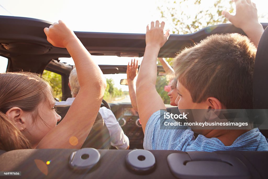 Grandparents Taking Grandchildren On Trip In Open Top Car Road Trip Stock Photo