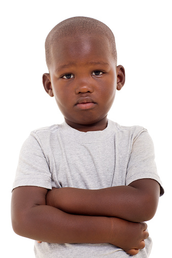 unhappy little african boy with arms crossed on white background