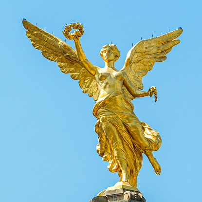 The golden sculpture over blue sky. The angel is part of the Independence monument of Mexico