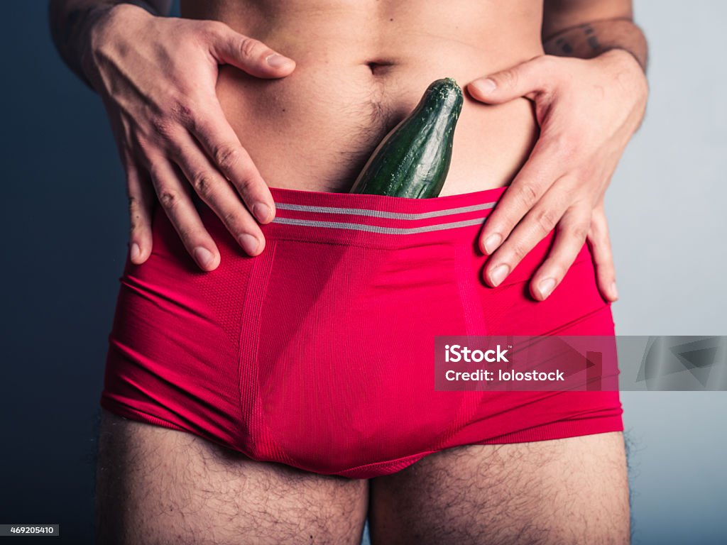 Young man with cucumber in his underpants A young man has stuffed a large cucumber down his underpants Penis Stock Photo