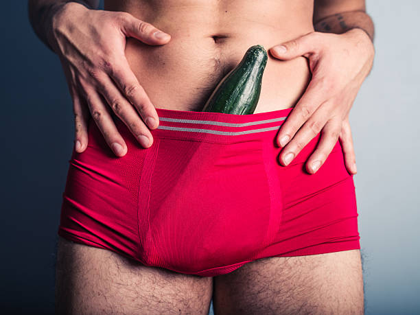 Young man with cucumber in his underpants stock photo