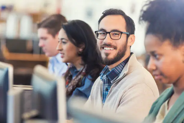 Photo of Happy Hispanic hipster man using comptuer in college computer class