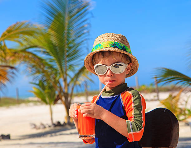 istock cute little boy drinking juice on the beach 469214822
