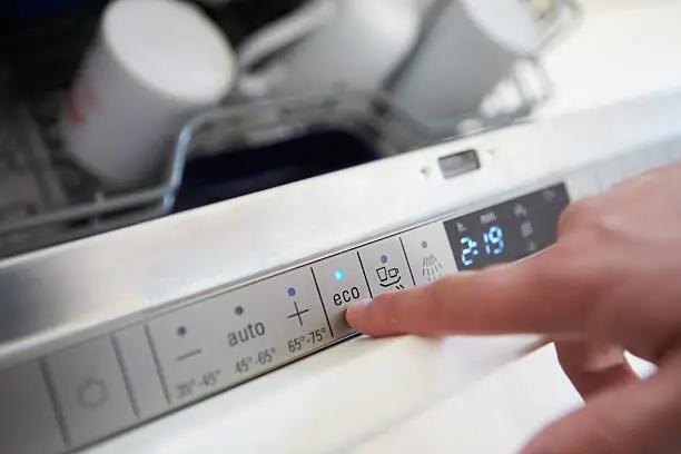 Photo of Close Up Of Man Setting Economy Cycle On Dishwasher